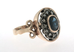 Anello in oro 18 kt e argento in stile antico con zaffiro ovale al centro contornato da diamanti