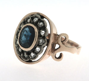 Anello in oro 18 kt e argento in stile antico con zaffiro ovale al centro contornato da diamanti