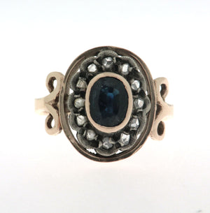 Anello in oro 18 kt e argento in stile antico con zaffiro ovale al centro contornato da diamanti